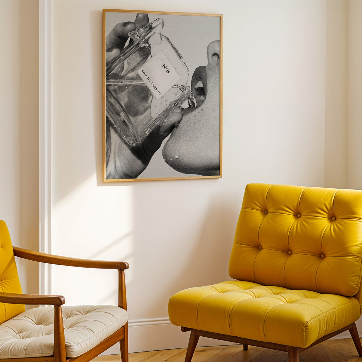 Cut-glass perfume bottle at a woman's lips print shown in a gold frame above a mustard yellow tufted armchair