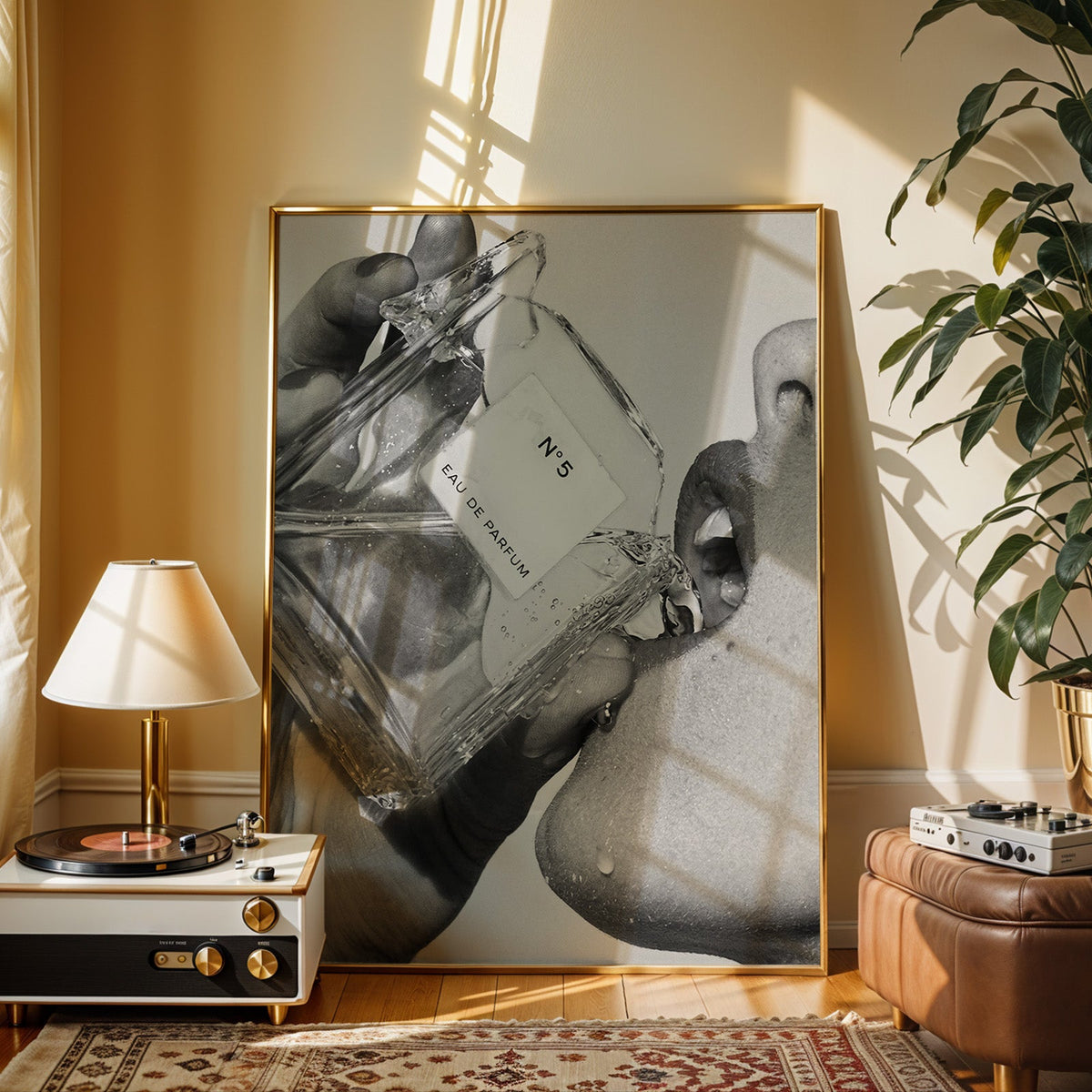 Cut-glass perfume bottle at a woman's lips print shown in a gold frame beside a record player and table lamp