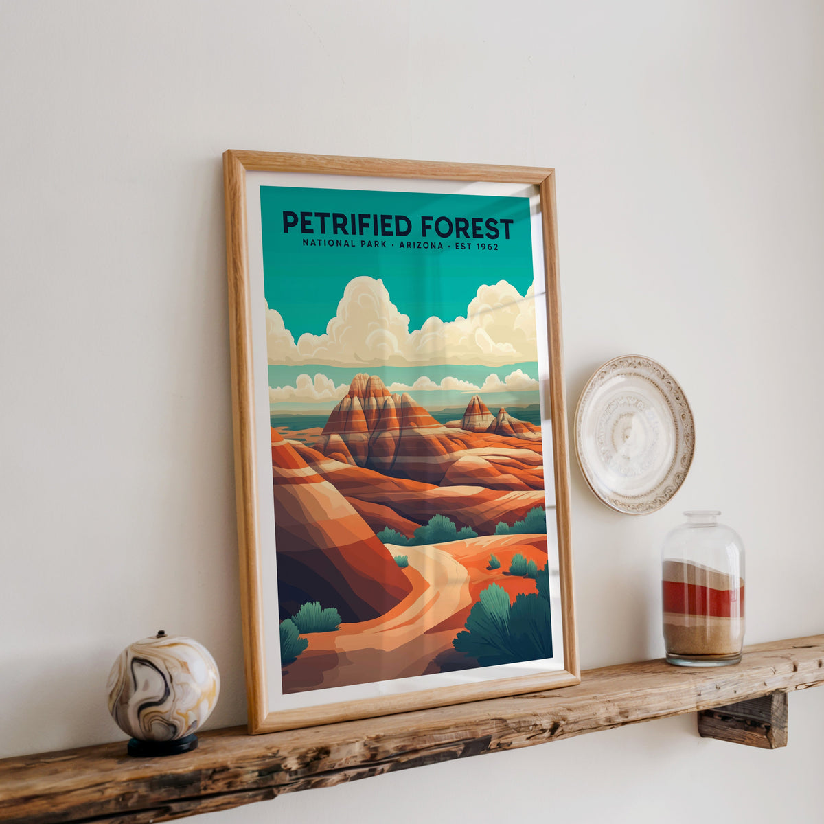 Petrified Forest National Park print in an oak frame on a wood shelf with ceramics and a sand-filled jar