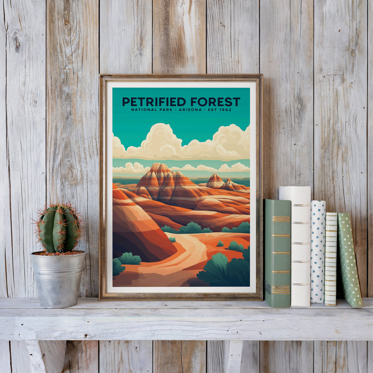 Petrified Forest poster in an antique gold frame against whitewashed planks beside books and a cactus