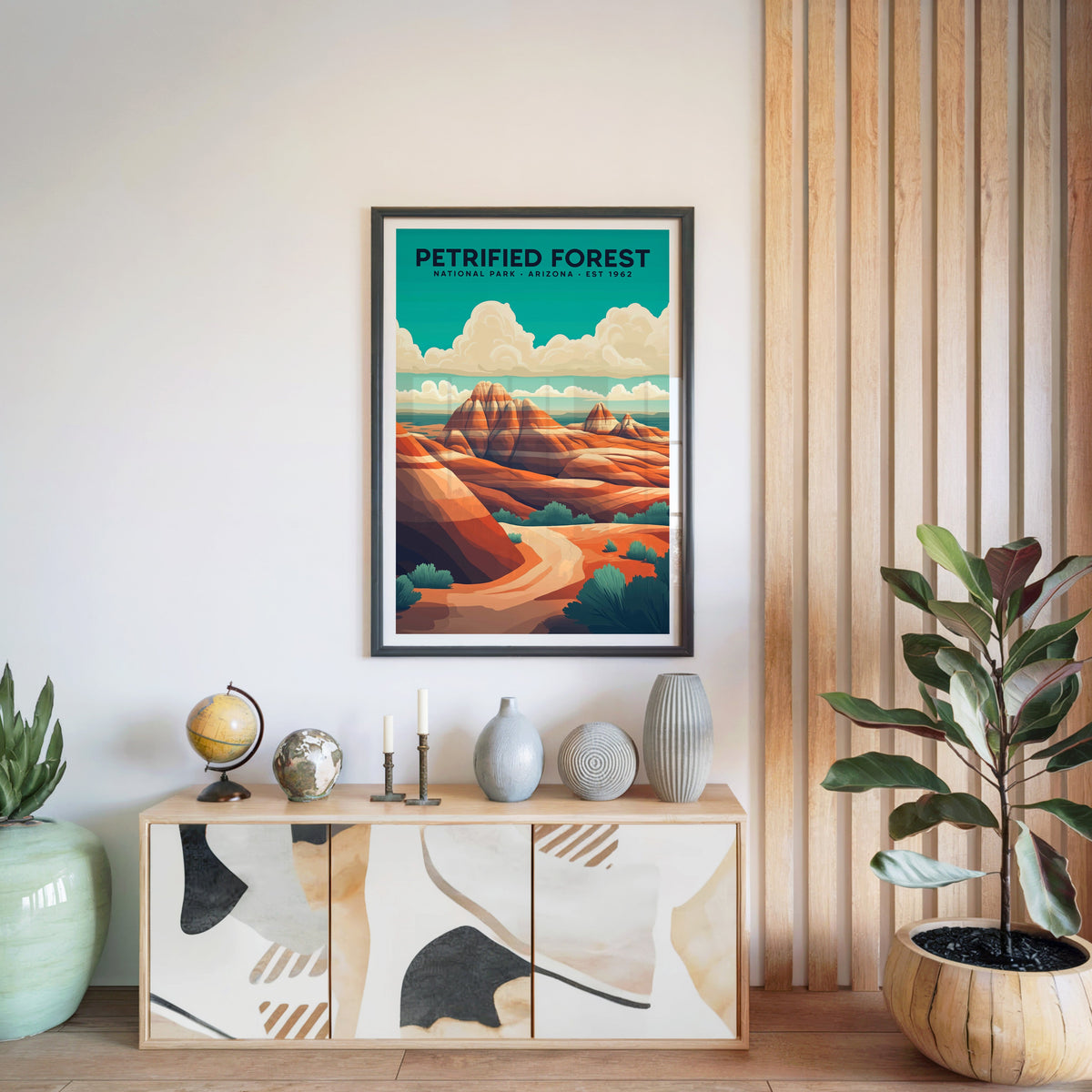 Petrified Forest National Park print in a black frame above a light wood sideboard with a globe and ceramic vases