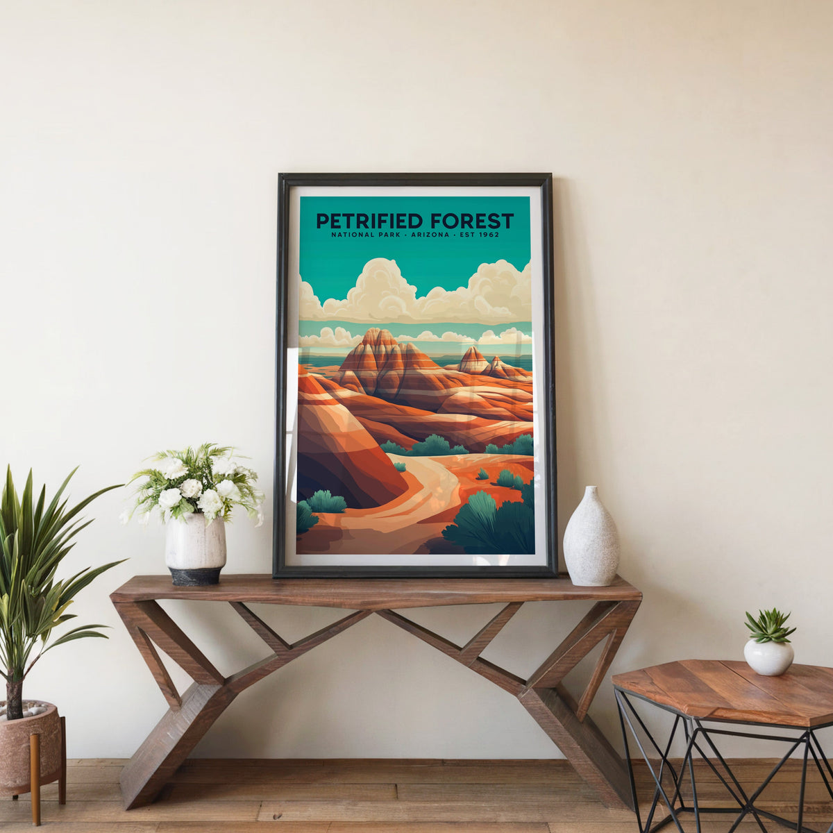 Petrified Forest poster in a black frame on an entryway console table beside white flowers and a yucca