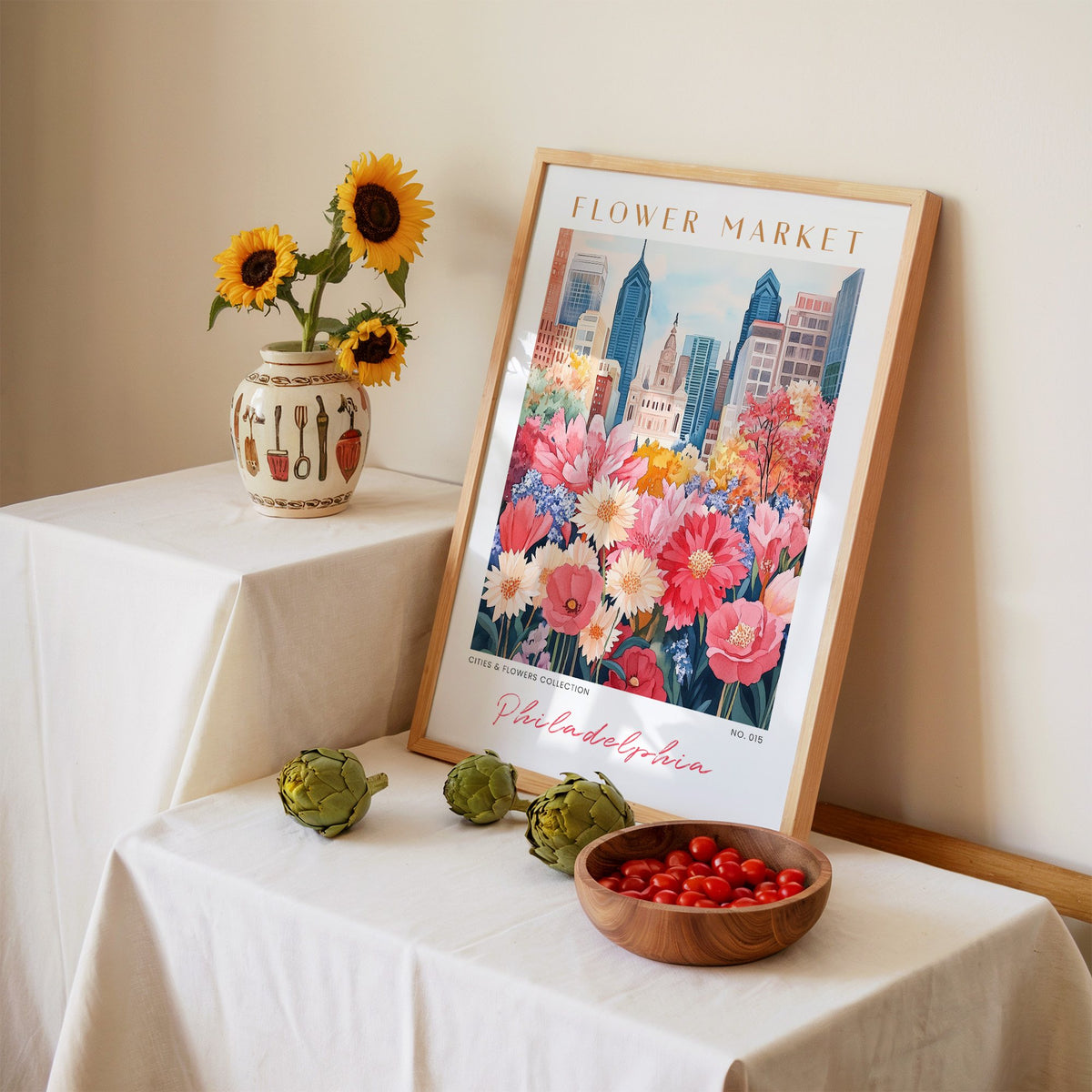 Philadelphia flower market print in an oak frame leaning on a linen-draped table beside a vase of sunflowers
