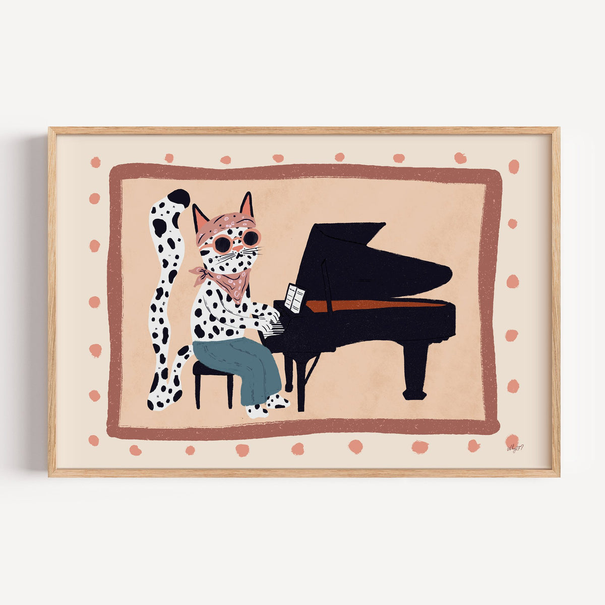 Spotted cat playing grand piano nursery print in a light oak frame on a plain white wall