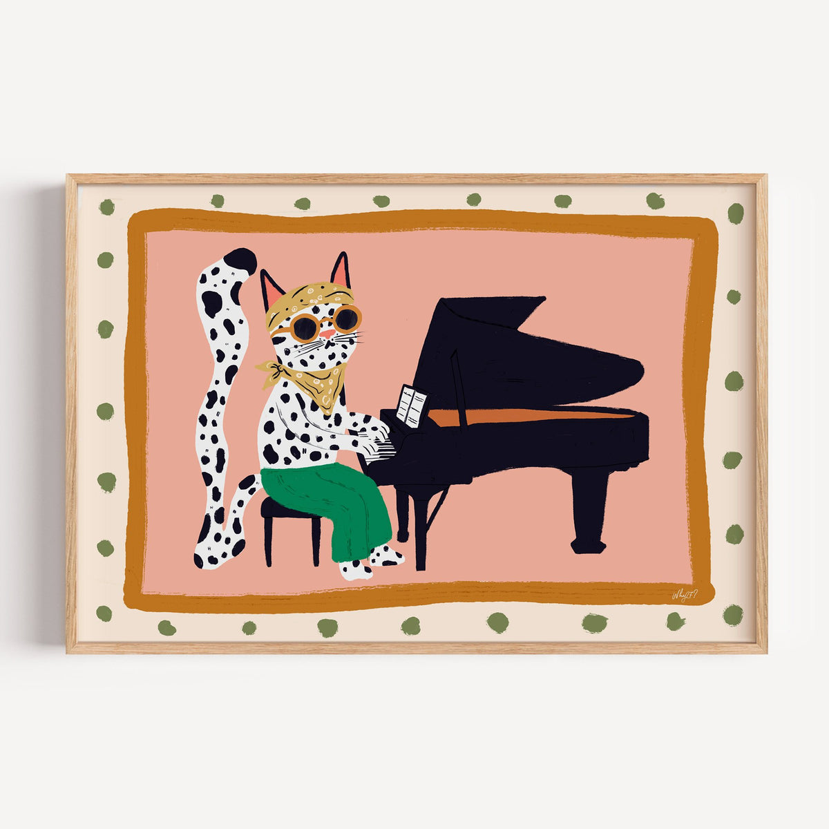 Spotted cat playing grand piano nursery print in a light oak frame on a plain white wall