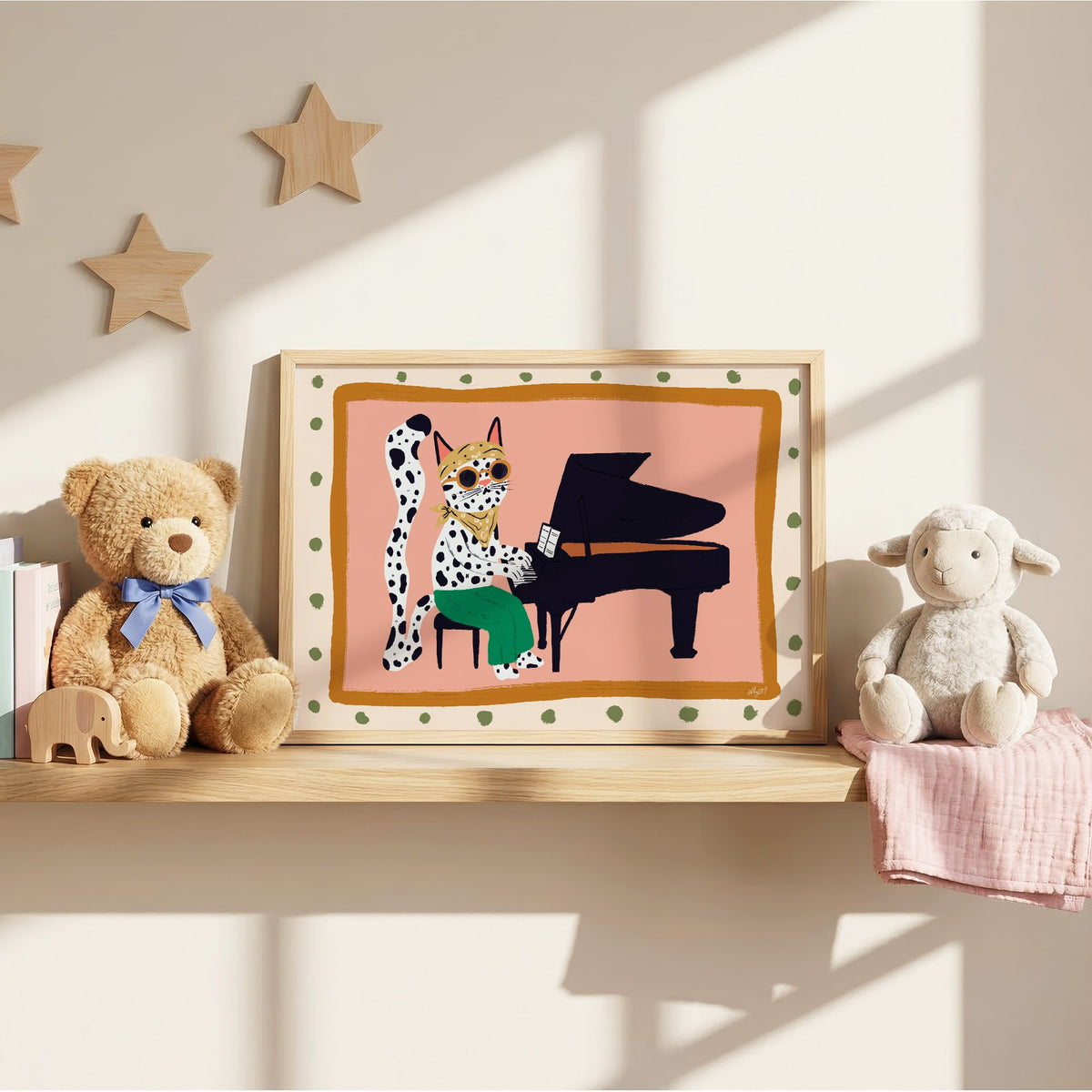 Spotted cat playing grand piano nursery print in an oak frame on a wall shelf between a teddy bear and a toy lamb