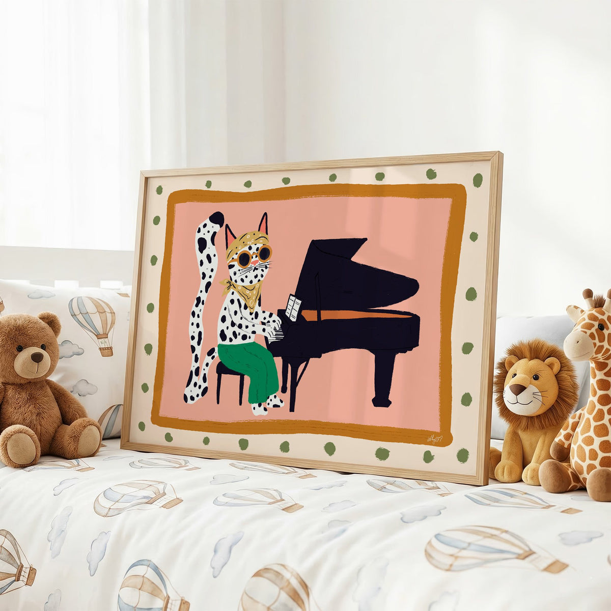 Spotted cat playing grand piano nursery print in an oak frame on a kids bed with hot air balloon bedding