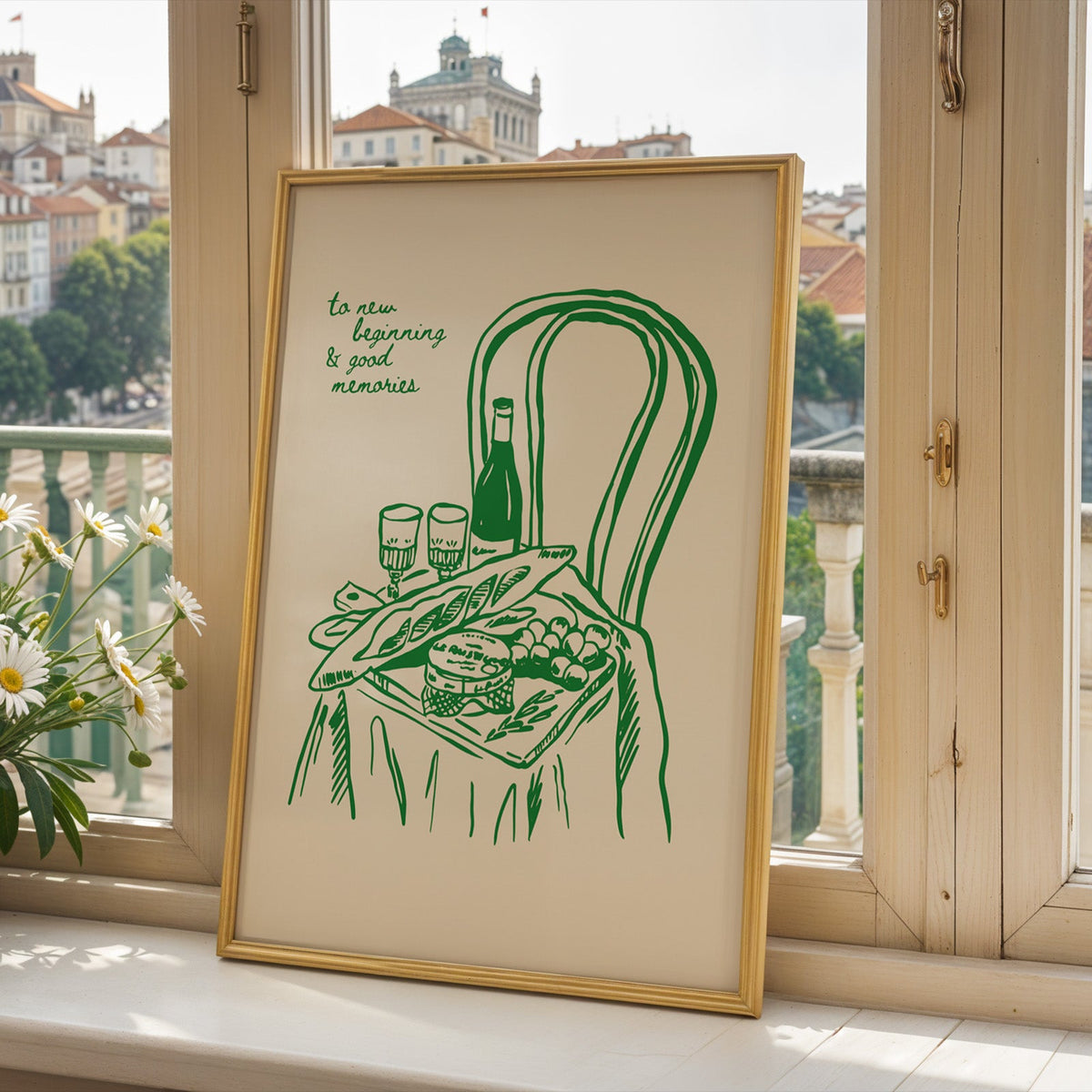 Picnic basket print in a gold frame on a window sill above a European hillside town