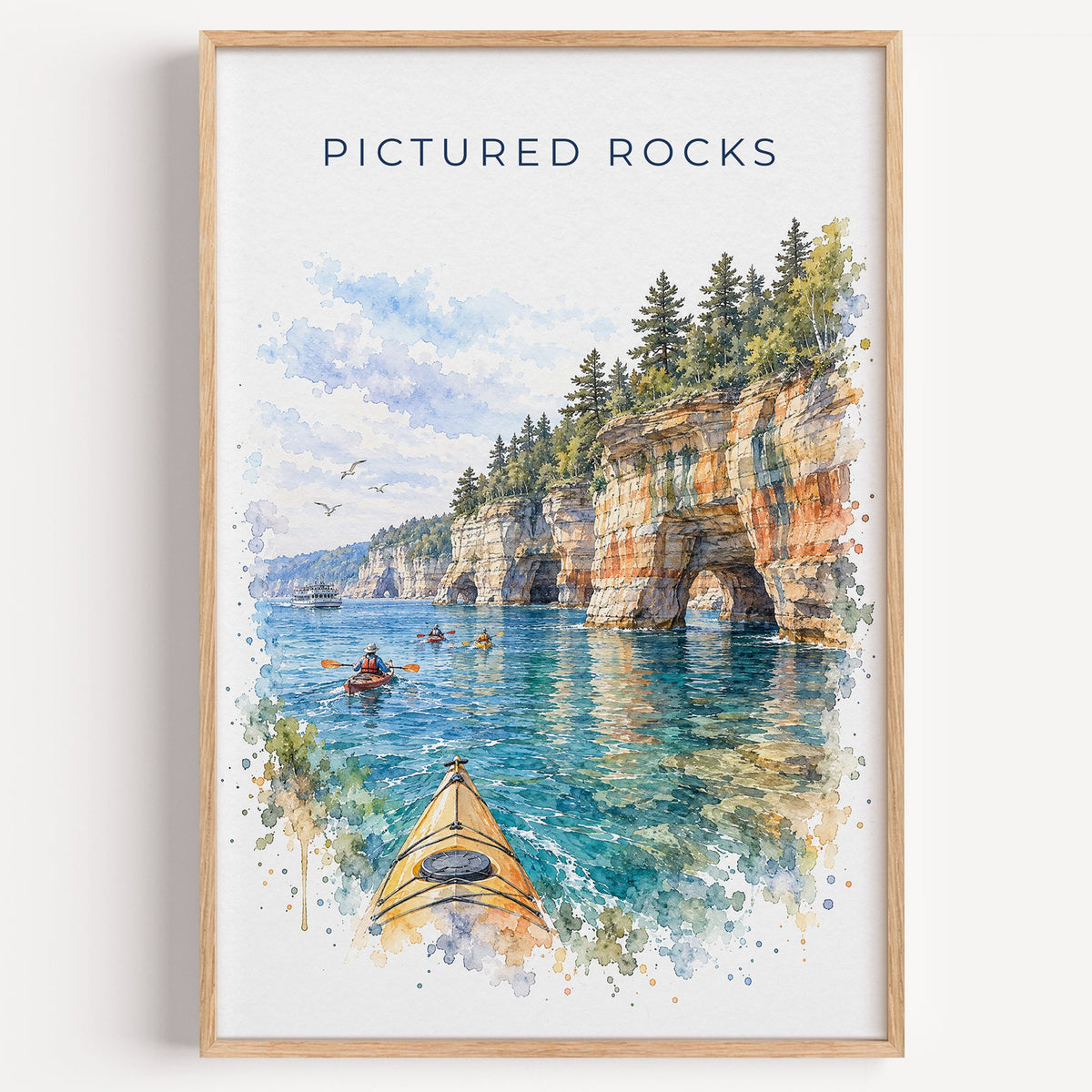 Pictured Rocks watercolor print in a light oak frame on a plain white wall