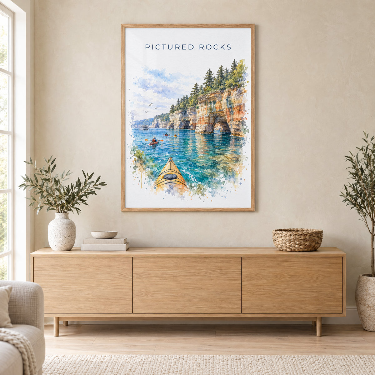 Pictured Rocks watercolor print in an oak frame above a light wood sideboard in a Scandinavian living room
