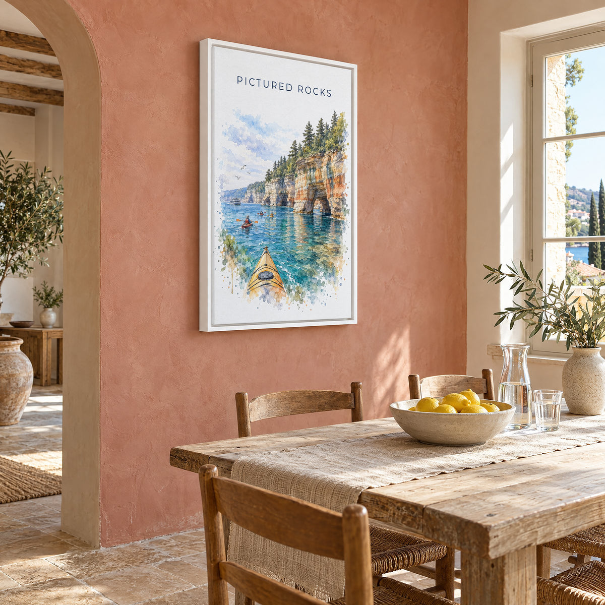Pictured Rocks watercolor print as a white floater canvas on a terracotta wall above a rustic dining table