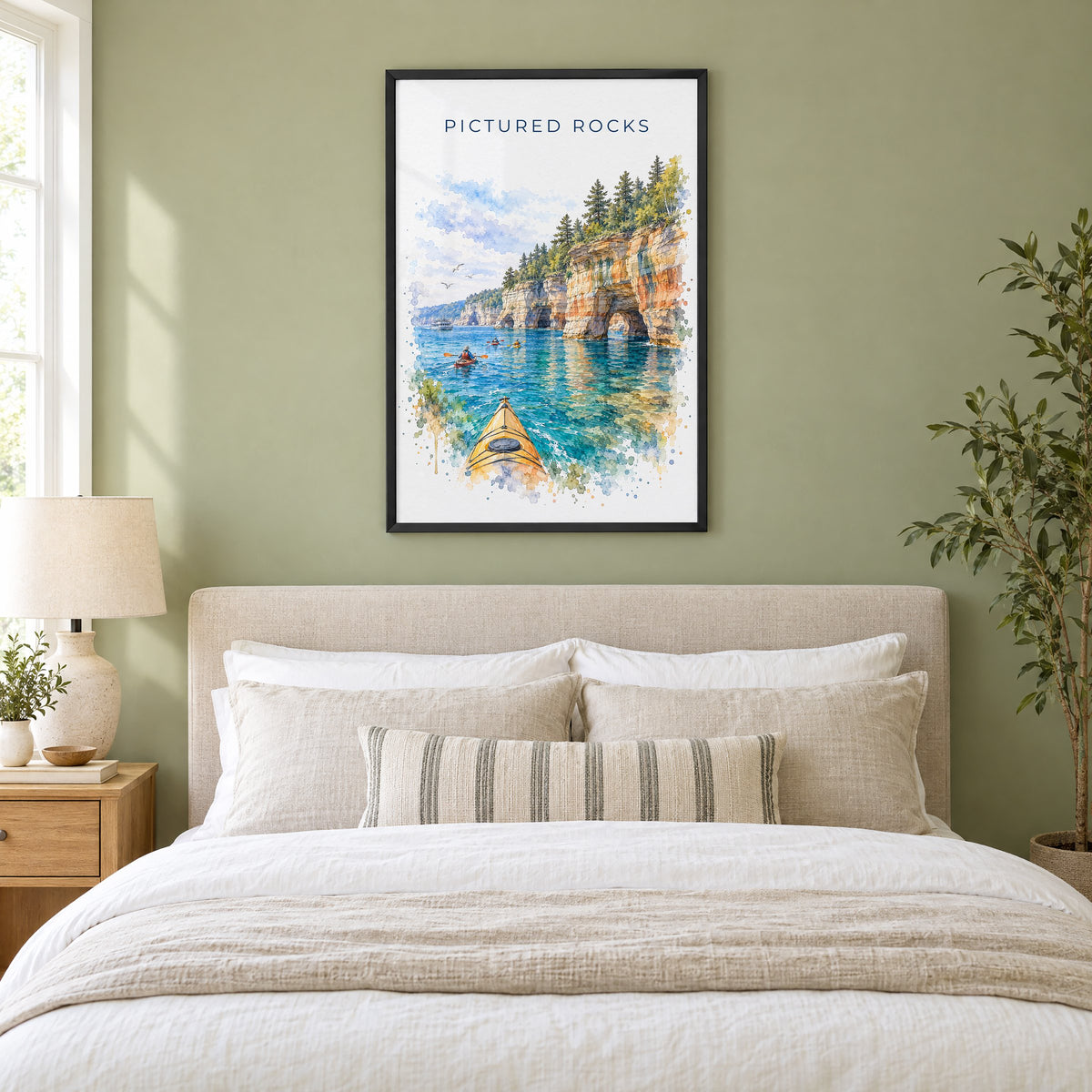 Pictured Rocks watercolor print in a black frame above an upholstered headboard in a sage green bedroom