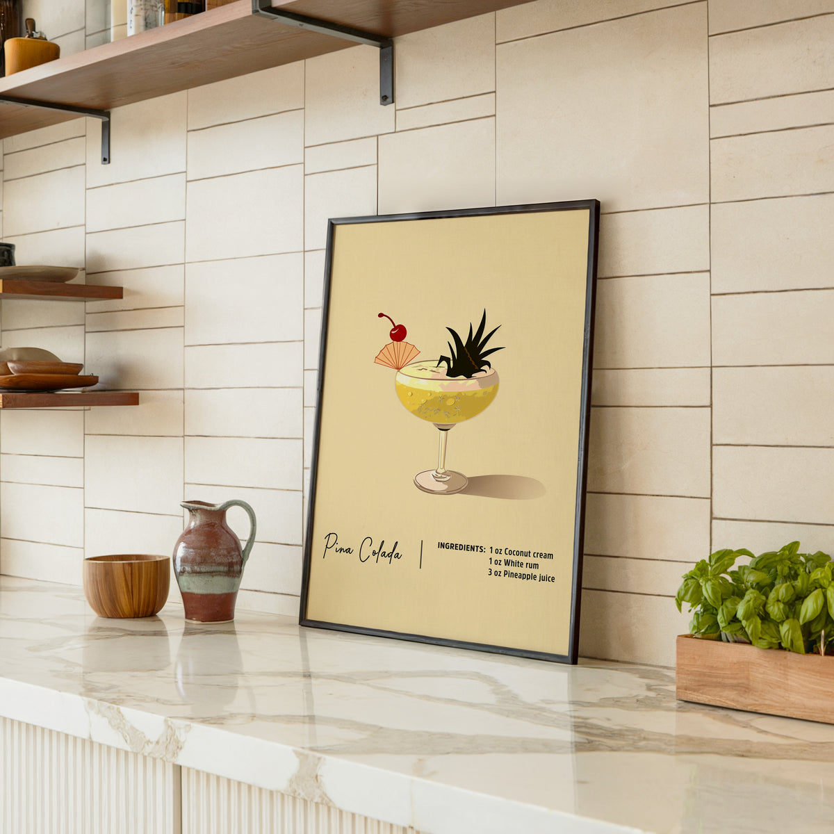 Pina colada recipe print in a black frame leaning on a marble counter in a tiled kitchen