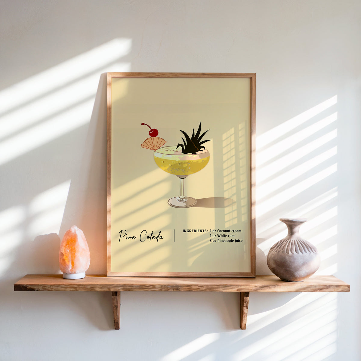 Pina colada recipe print in an oak frame on a live-edge shelf beside a salt lamp