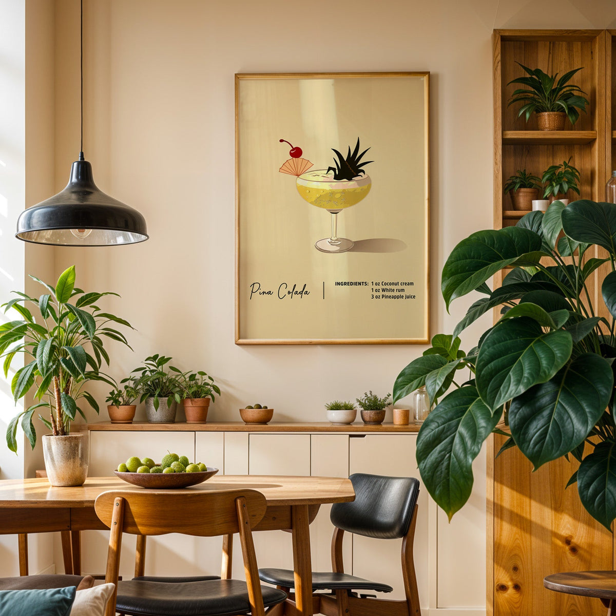 Pina colada recipe print in an oak frame in a dining room above a plant-lined sideboard