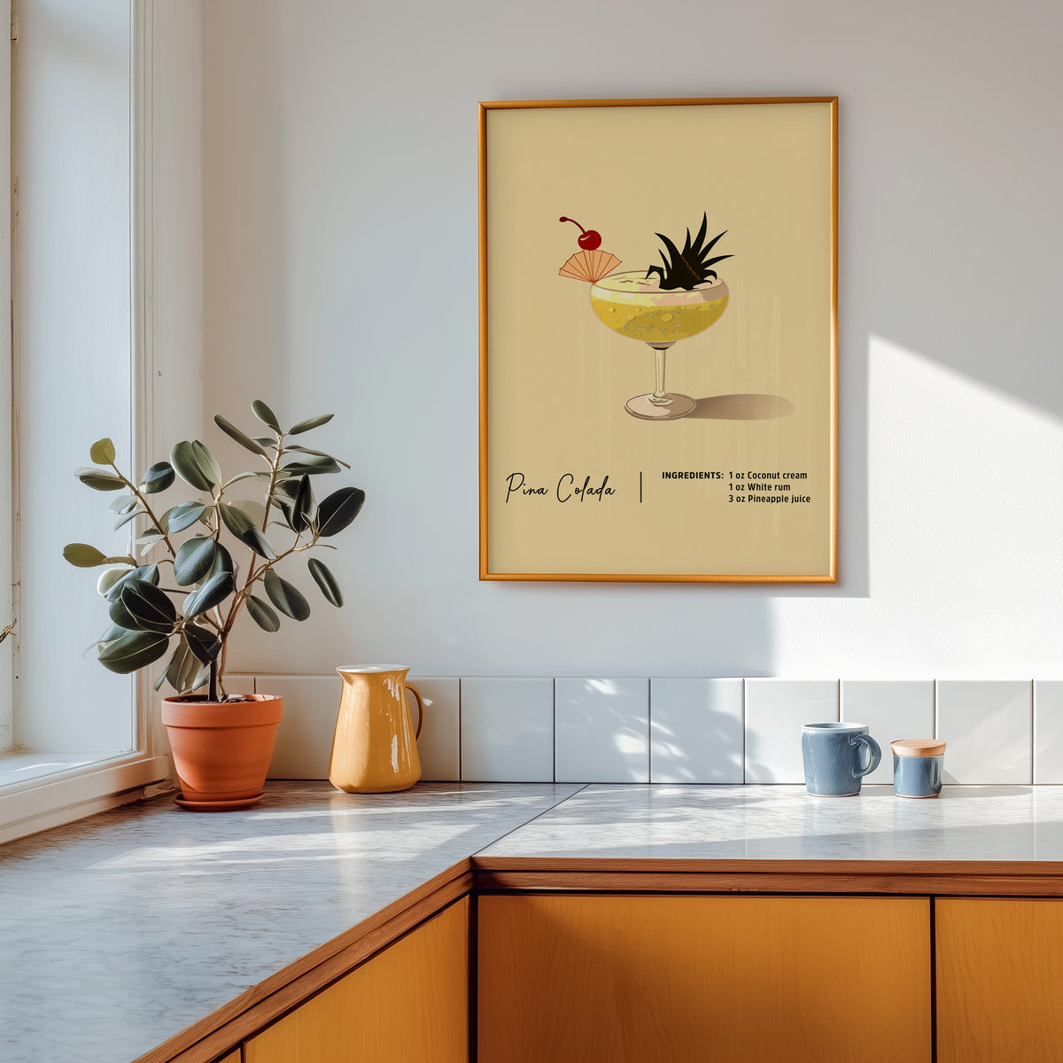 Pina colada recipe print shown in a gold frame above a marble counter in a tan kitchen