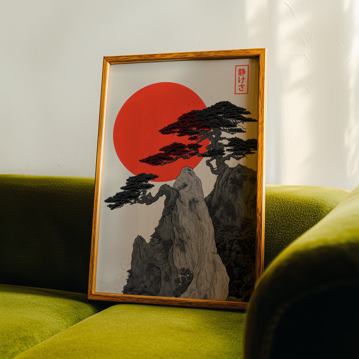 Ink pine cliff with red sun print in an oak frame propped on a green velvet sofa