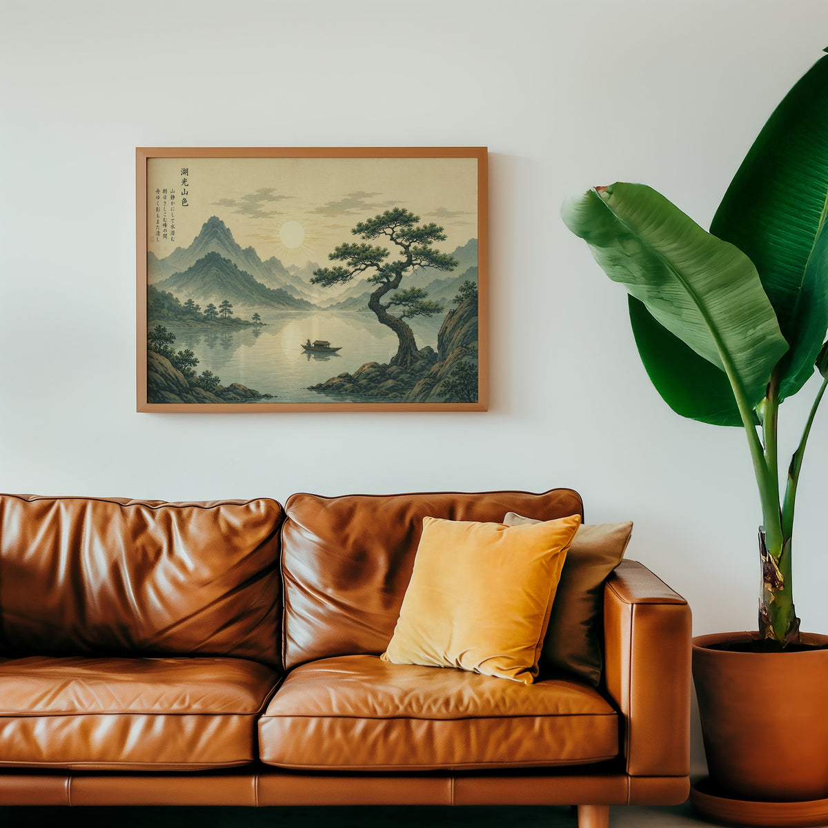 Pine tree over a mountain lake at sunrise print in a warm oak frame above a cognac leather sofa with a mustard pillow