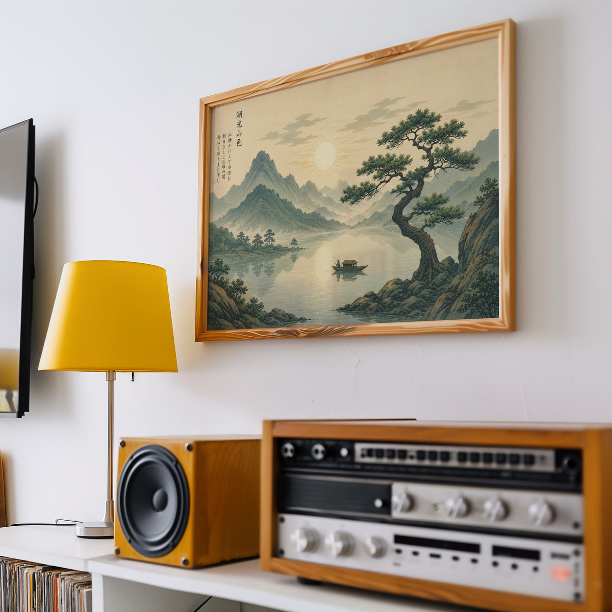 Pine tree over a mountain lake at sunrise print in a pine frame above a vintage stereo and a yellow table lamp