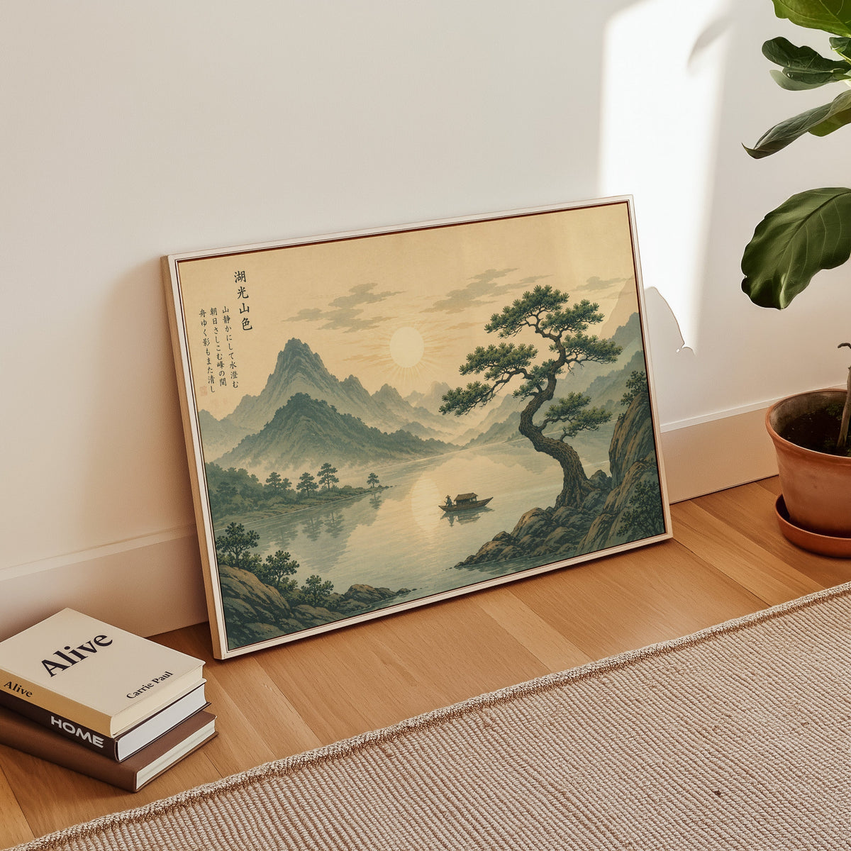 Pine tree over a mountain lake at sunrise print in a white floater frame leaning on a wood floor beside stacked books