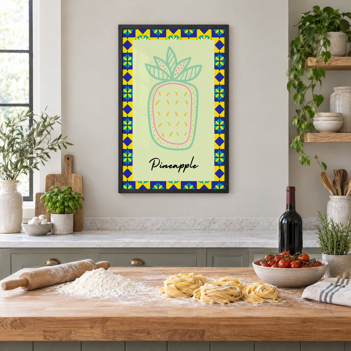 Pineapple mint line-art tile border print in a black frame above a butcher-block island with fresh pasta, flour and cherry tomatoes