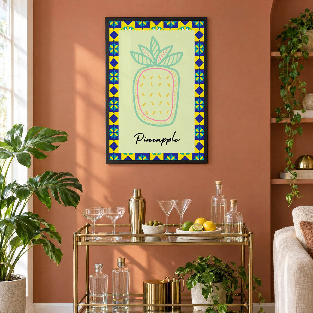 Pineapple mint line-art tile border print in a black frame on a terracotta wall above a brass bar cart with coupes and citrus