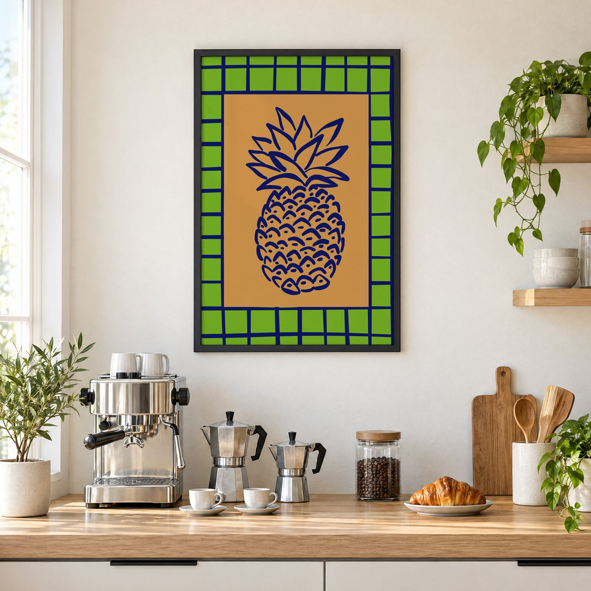 Pineapple navy line on ochre with green grid print in a black frame above a home espresso bar with moka pots and espresso cups