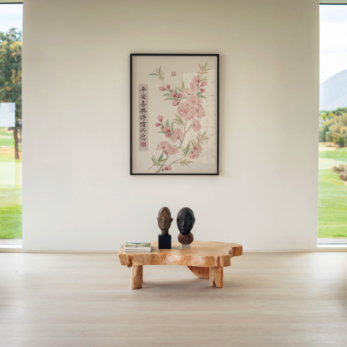 pink blossom with calligraphy blessing print in a black frame above a live-edge wood coffee table between garden windows