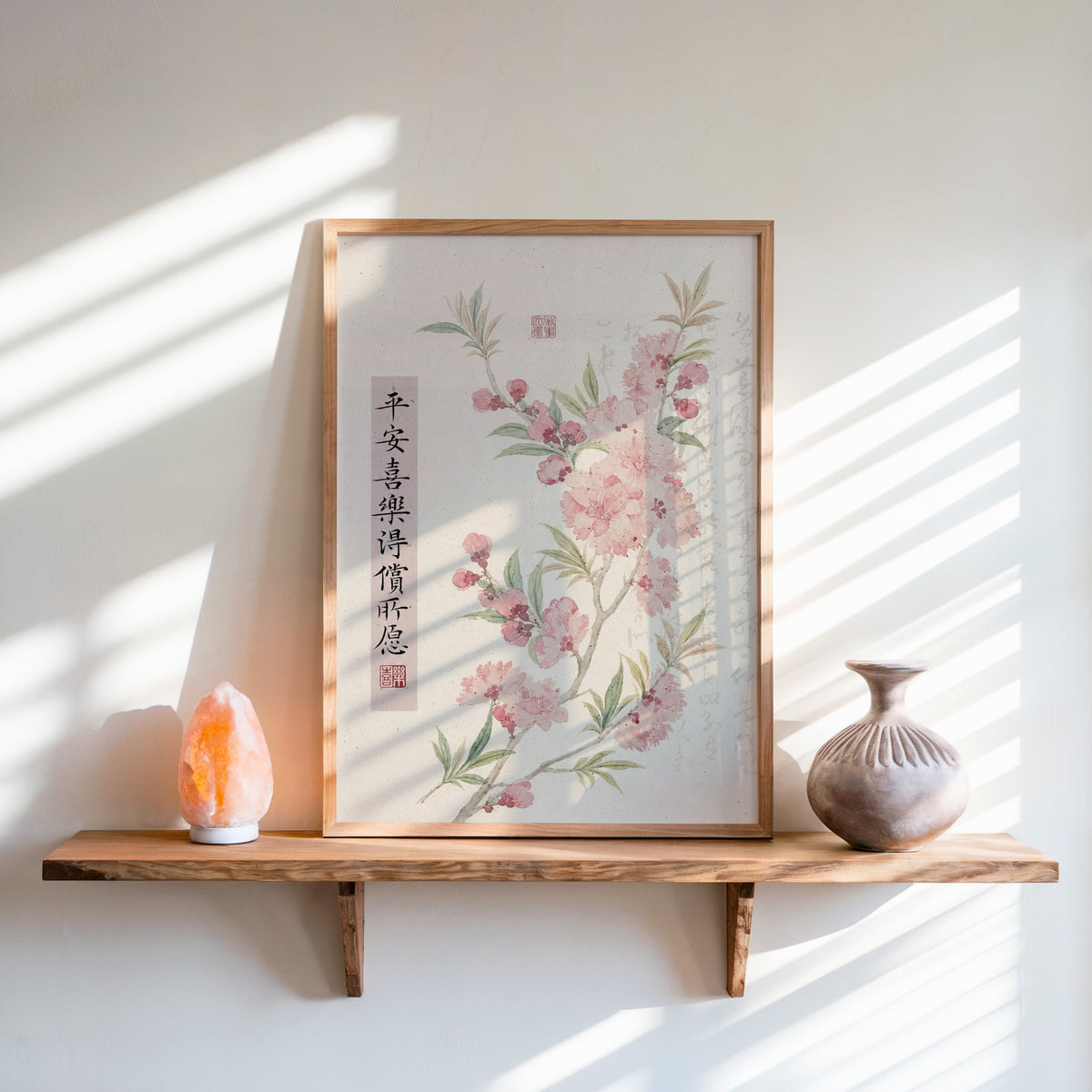 pink blossom with calligraphy blessing print in an oak frame on a live-edge wall shelf with a salt lamp and clay vase