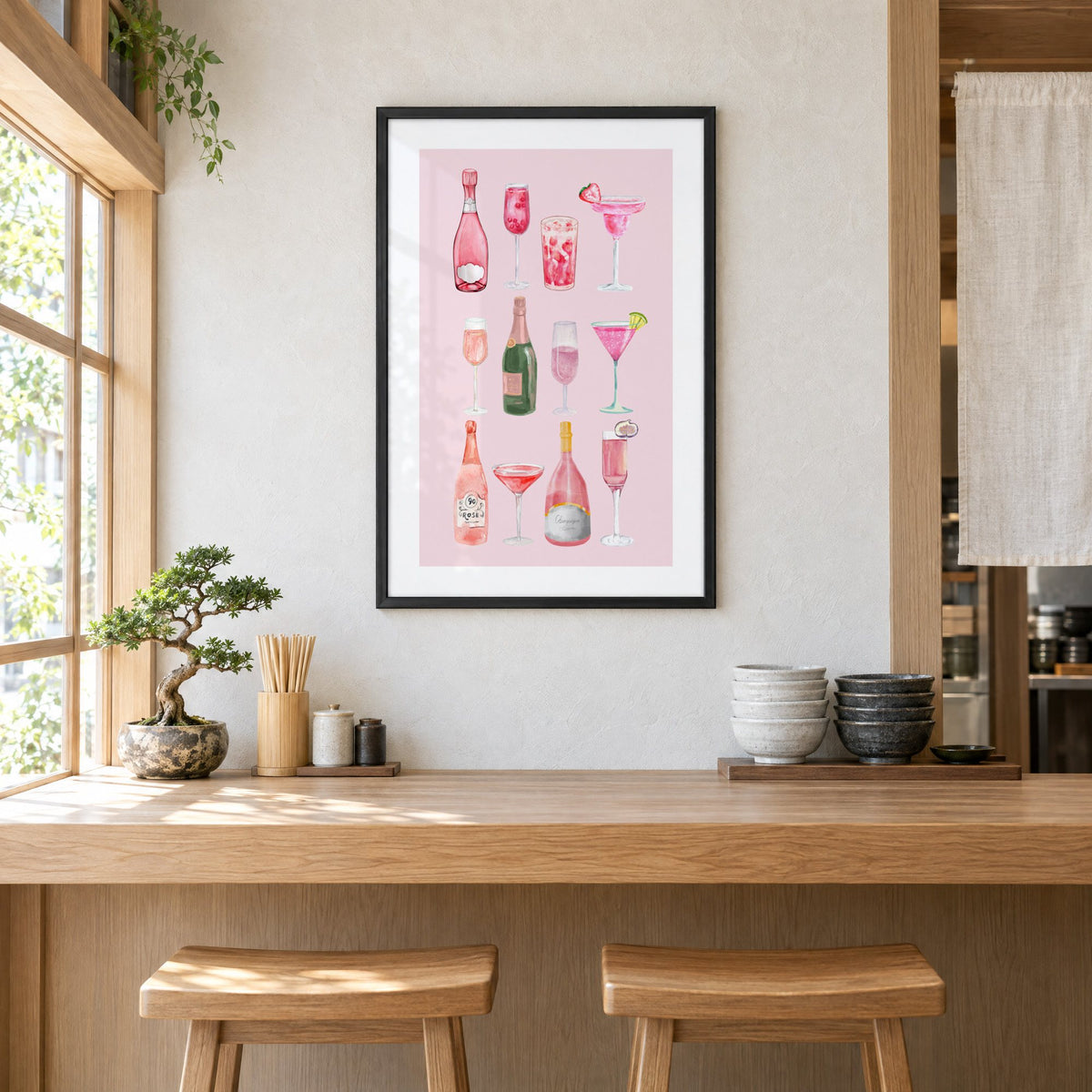 pink champagne bottles and cocktails watercolor print in a black frame above a light wood ramen counter with stools and stacked bowls