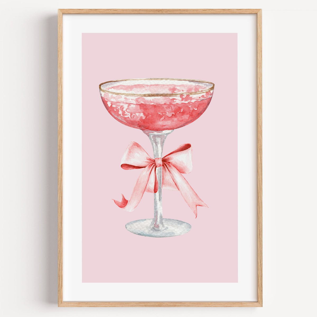 gold rim champagne coupe satin bow print in a light oak frame on a plain white wall