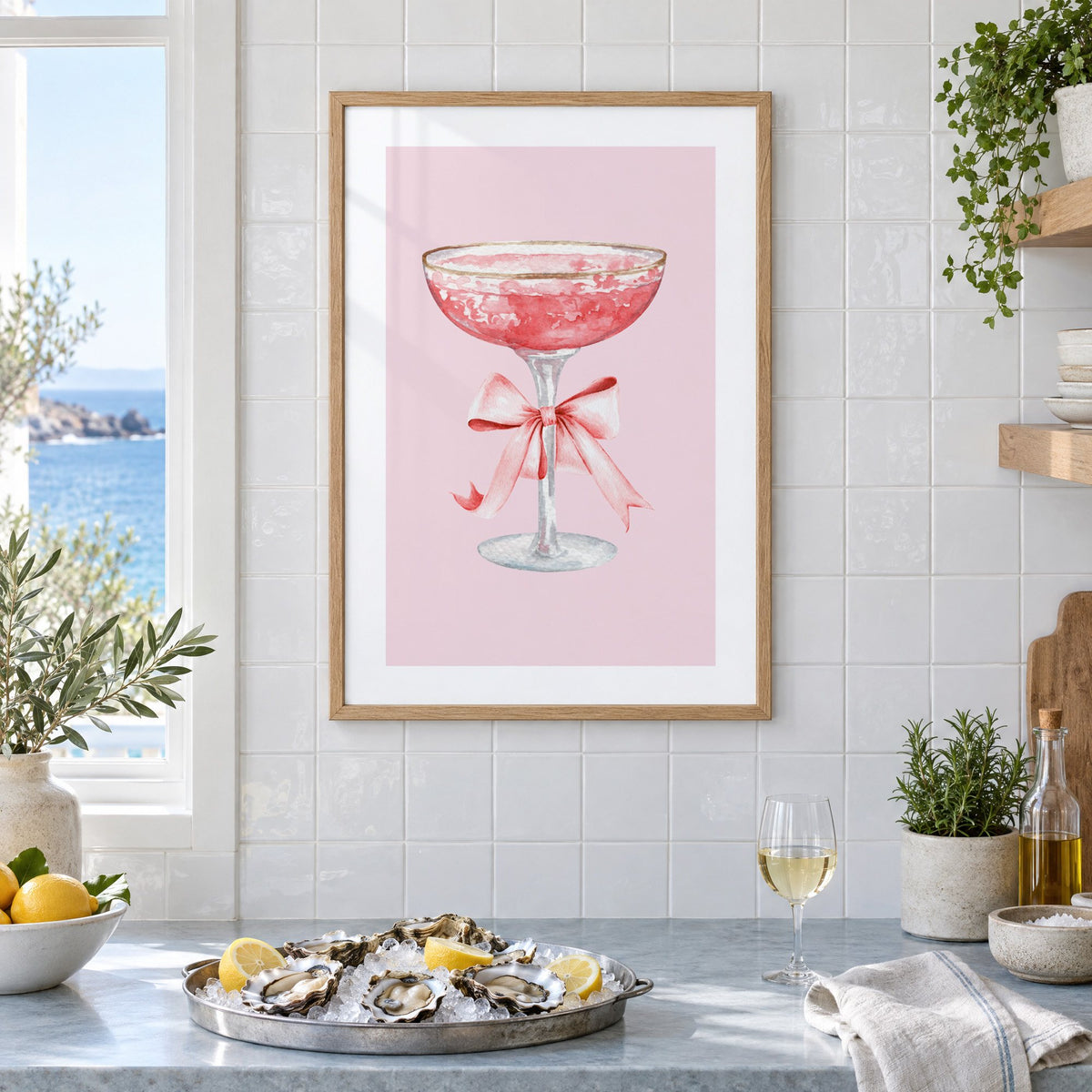 gold rim champagne coupe satin bow print in an oak frame on white tiles above a marble counter with oysters and lemons by a sea view