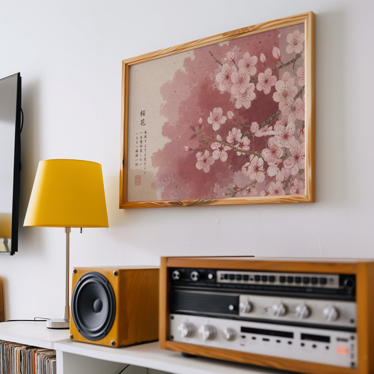 Pink cherry blossom with Japanese verse print in a pine frame above a vintage stereo and a yellow table lamp