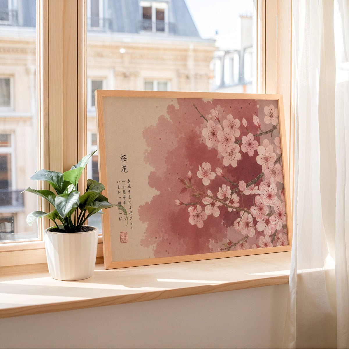 Pink cherry blossom with Japanese verse print in a light wood frame leaning on a sunny windowsill by sheer curtains