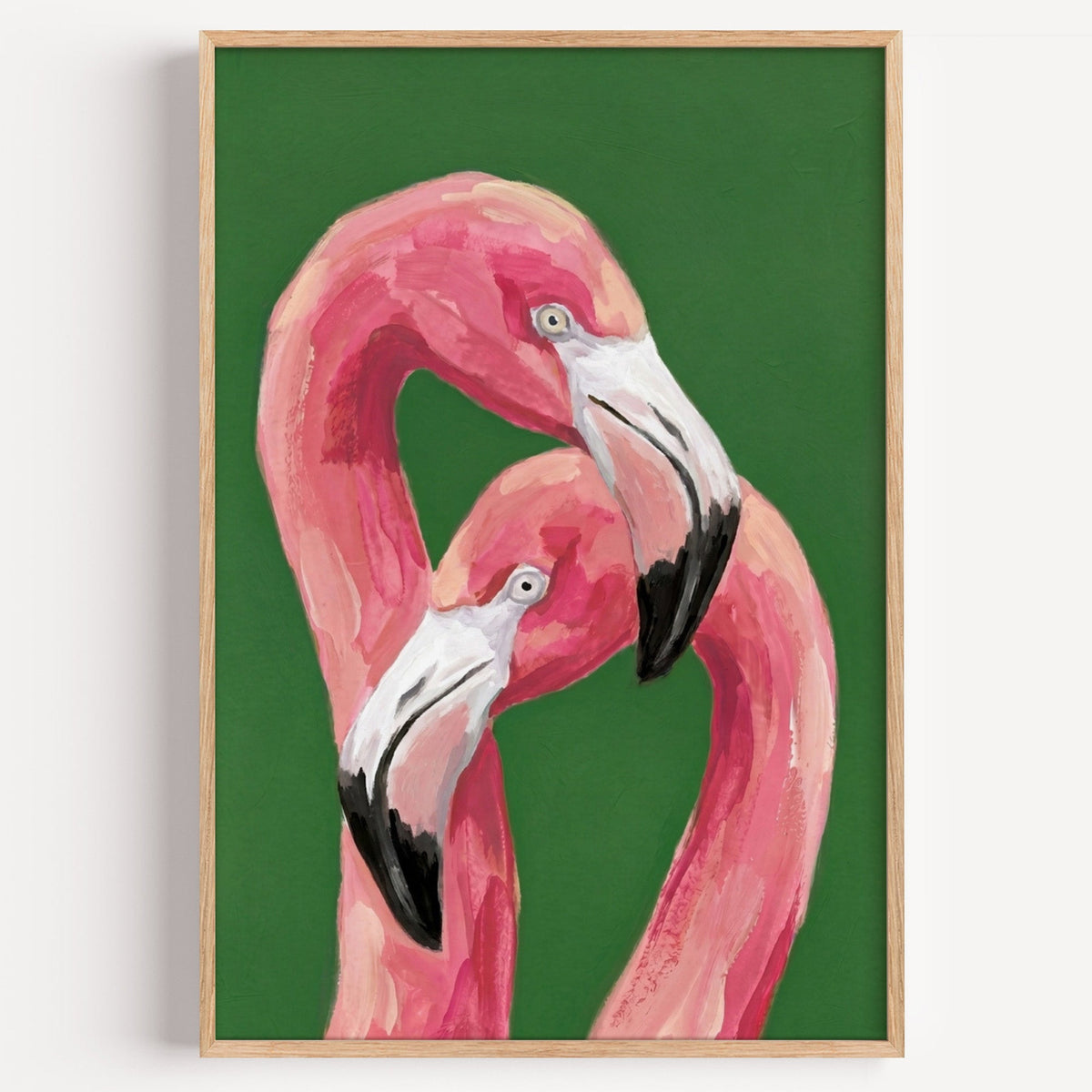 Pink flamingo pair print in a light oak frame on a plain white wall
