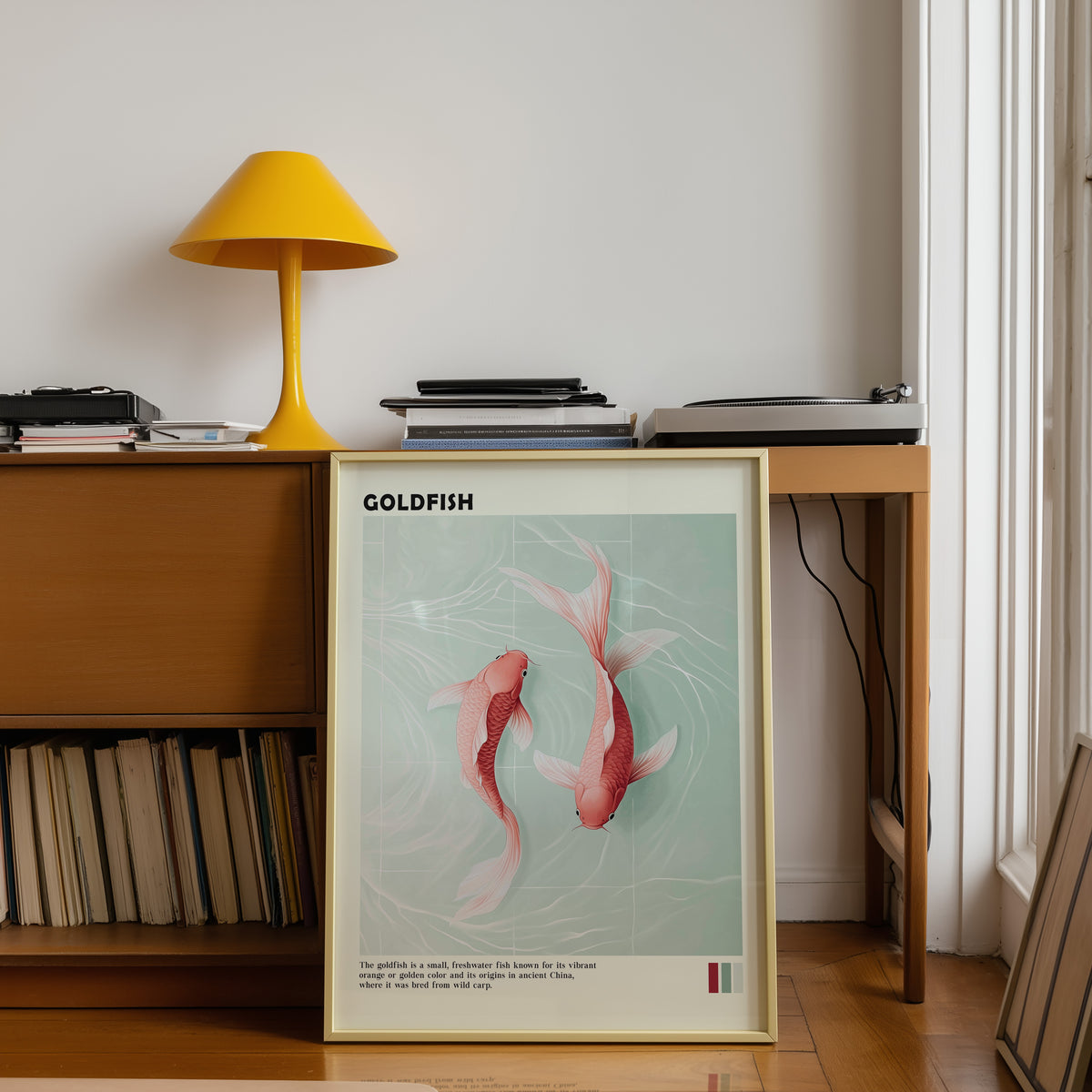 Pink goldfish pair on mint water print shown in a gold frame below a teak desk with a yellow lamp