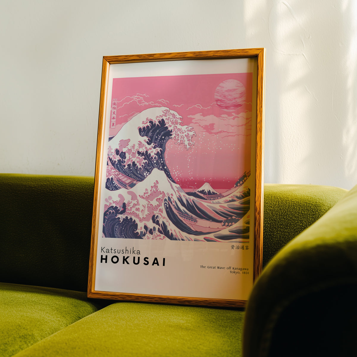 Pink Great Wave off Kanagawa print in an oak frame propped on a green velvet sofa