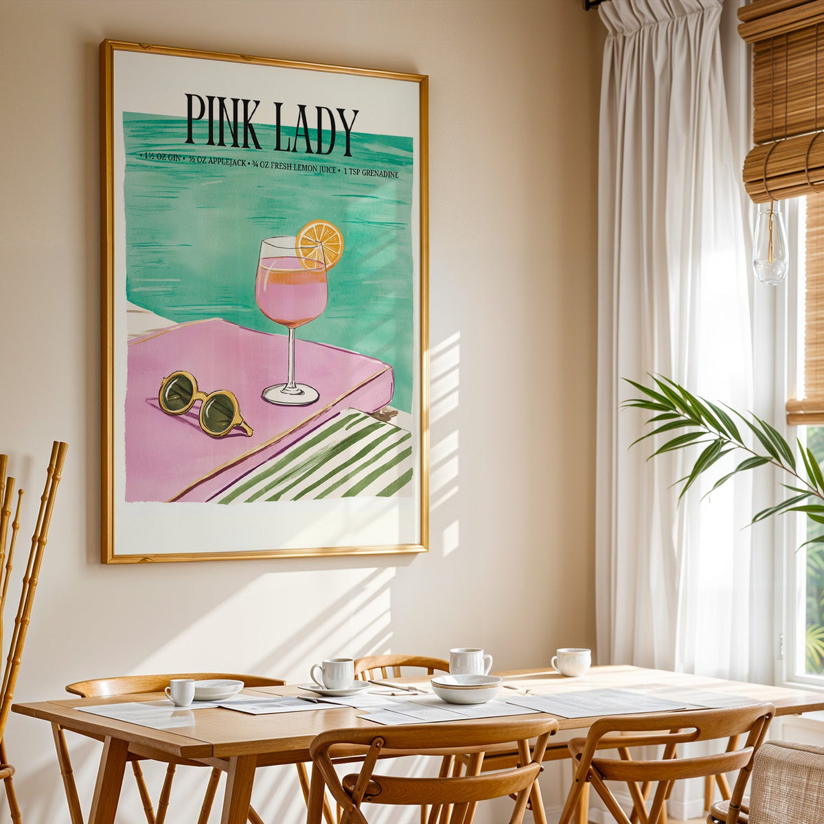 Pink Lady cocktail print shown in a gold frame above a breakfast table by a curtained window