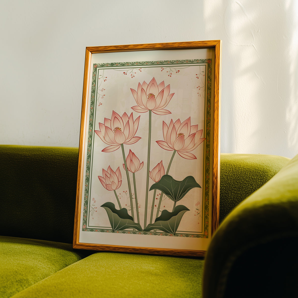 Five pink lotus flowers print in an oak frame propped on a green velvet sofa