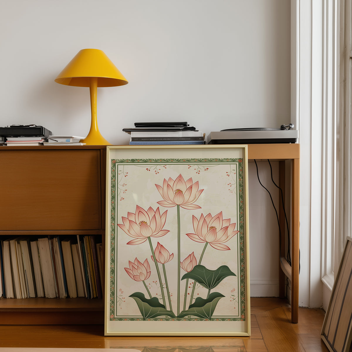 Five pink lotus flowers print shown in a gold frame below a teak desk with a yellow lamp