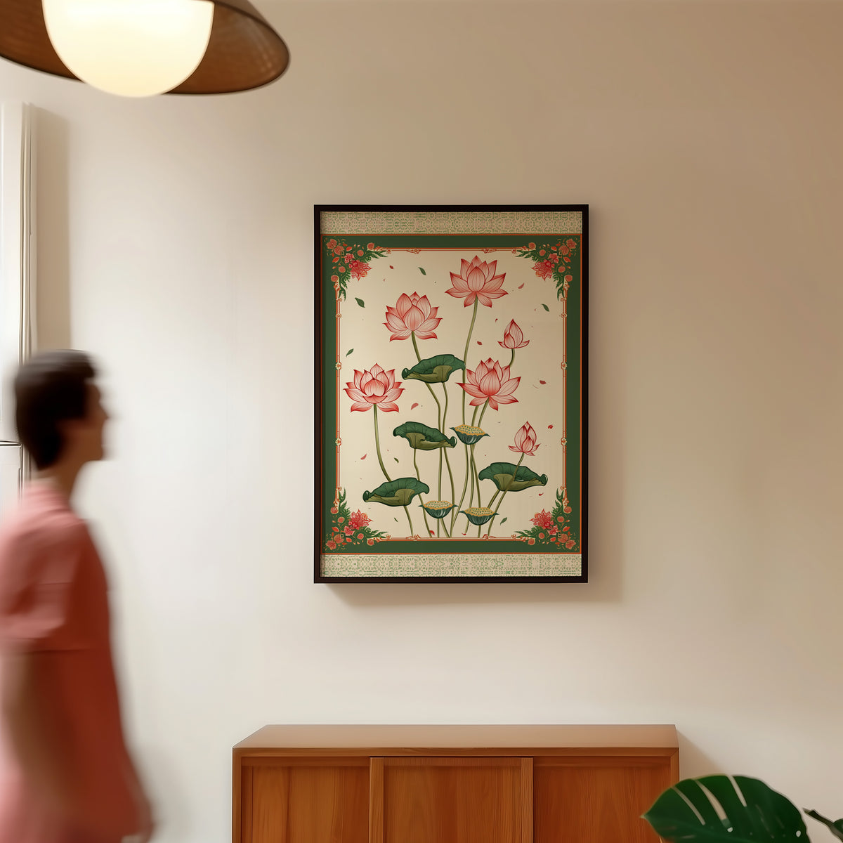 Pink lotus with green ornamental border print in a black frame in a hallway under a rattan pendant