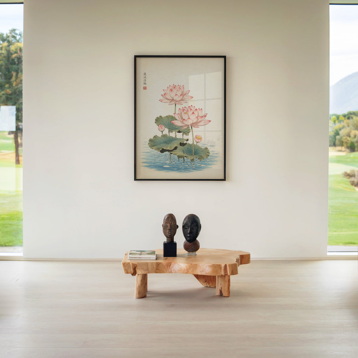 pink lotus pond print in a black frame above a live-edge wood coffee table between garden windows