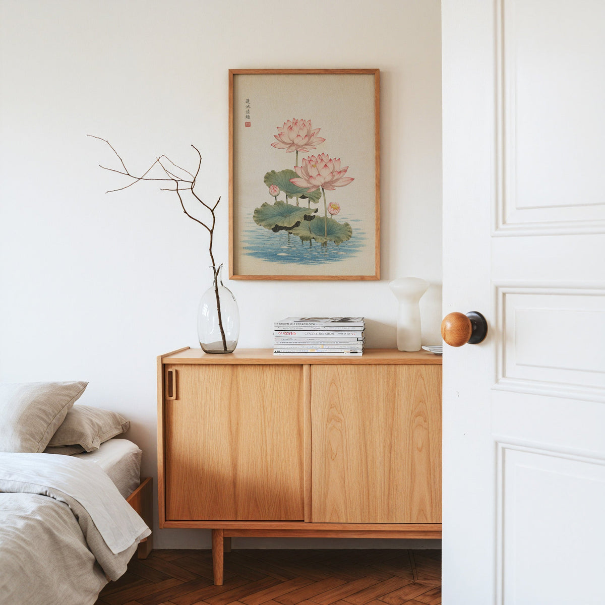 pink lotus pond print in an oak frame above an oak sideboard in a bedroom with linen bedding