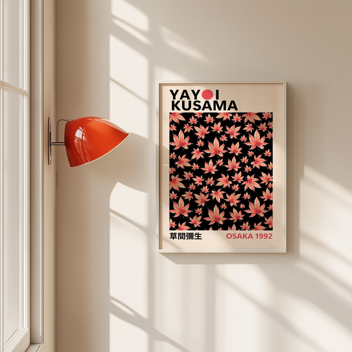 Yayoi Kusama inspired pink maple leaves on black print in a white frame beside a red wall sconce
