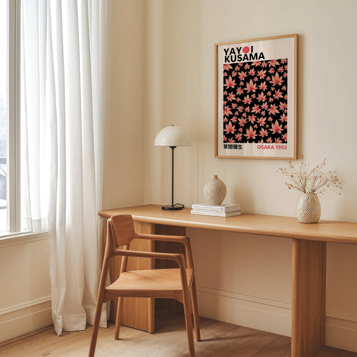 Yayoi Kusama inspired pink maple leaves on black print in an oak frame above an oak desk with a dome lamp