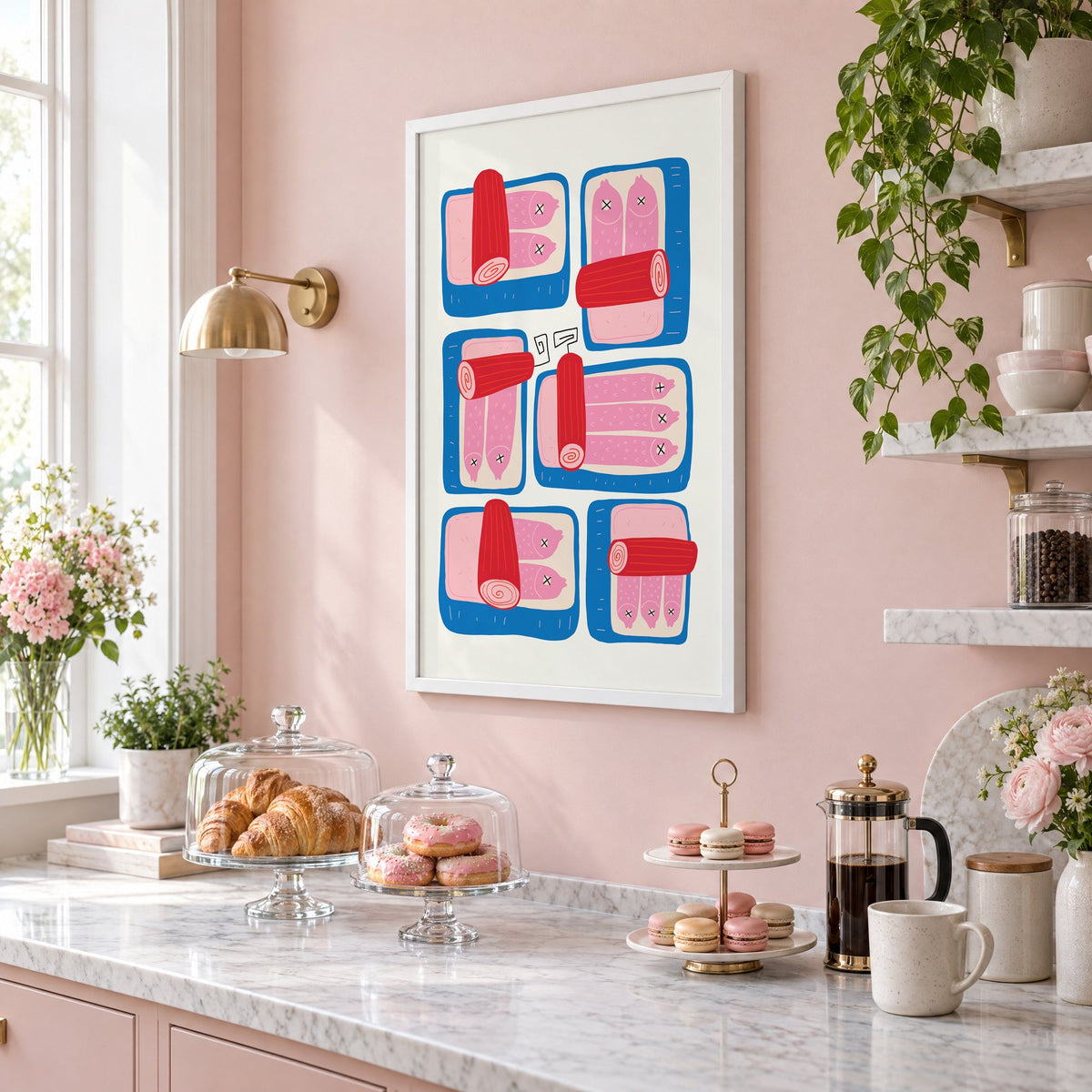 Six blue sardine tins pink fish print in a white frame on a blush pink wall above a patisserie counter with croissants and macarons, seen at an angle