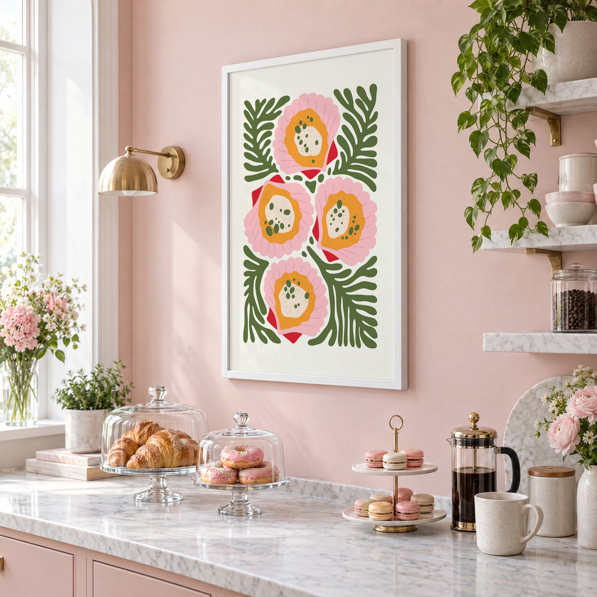 pink scallop shells green seaweed print in a white frame on a blush pink wall above a patisserie counter with croissants and macarons, seen at an angle