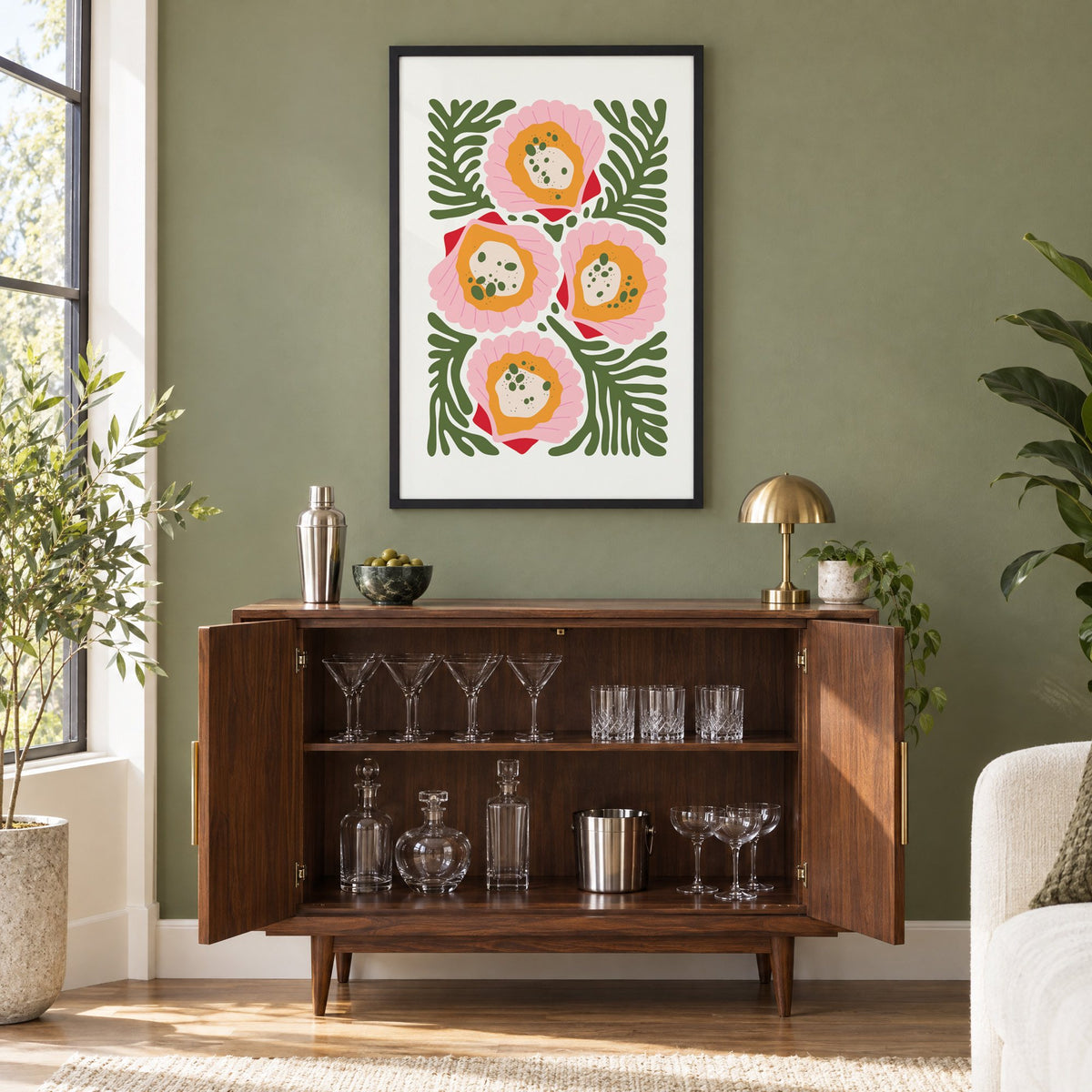 pink scallop shells green seaweed print in a black frame on an olive green wall above a walnut bar cabinet with glassware