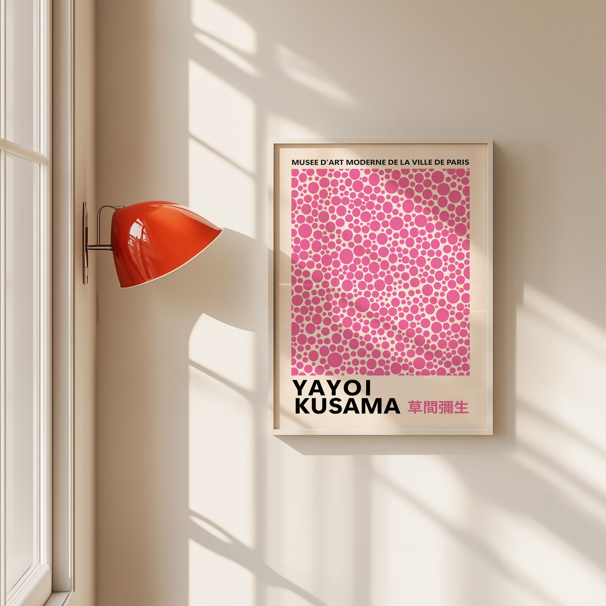 Yayoi Kusama inspired pink polka dot pattern print in a white frame by a red wall lamp