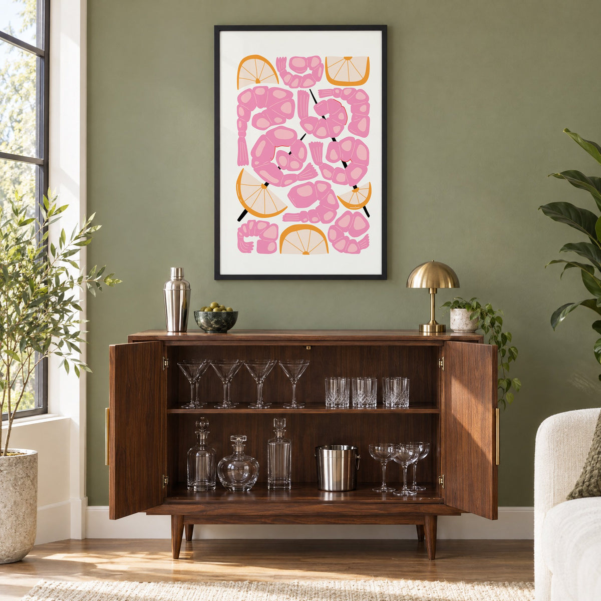 pink shrimp skewers orange wedges print in a black frame on an olive green wall above a walnut bar cabinet with glassware